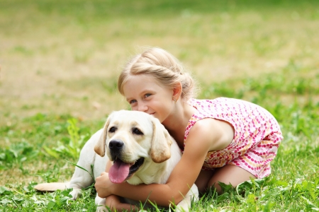 a little blond girl with her pet dog outdooors in park